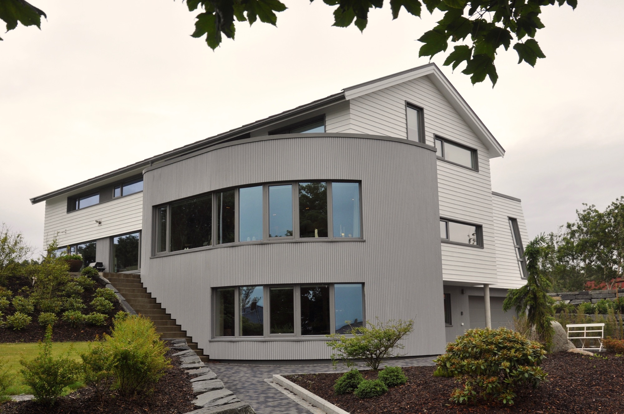 Stue med buet panoramavindu ut mot kulturlandskapet i sør