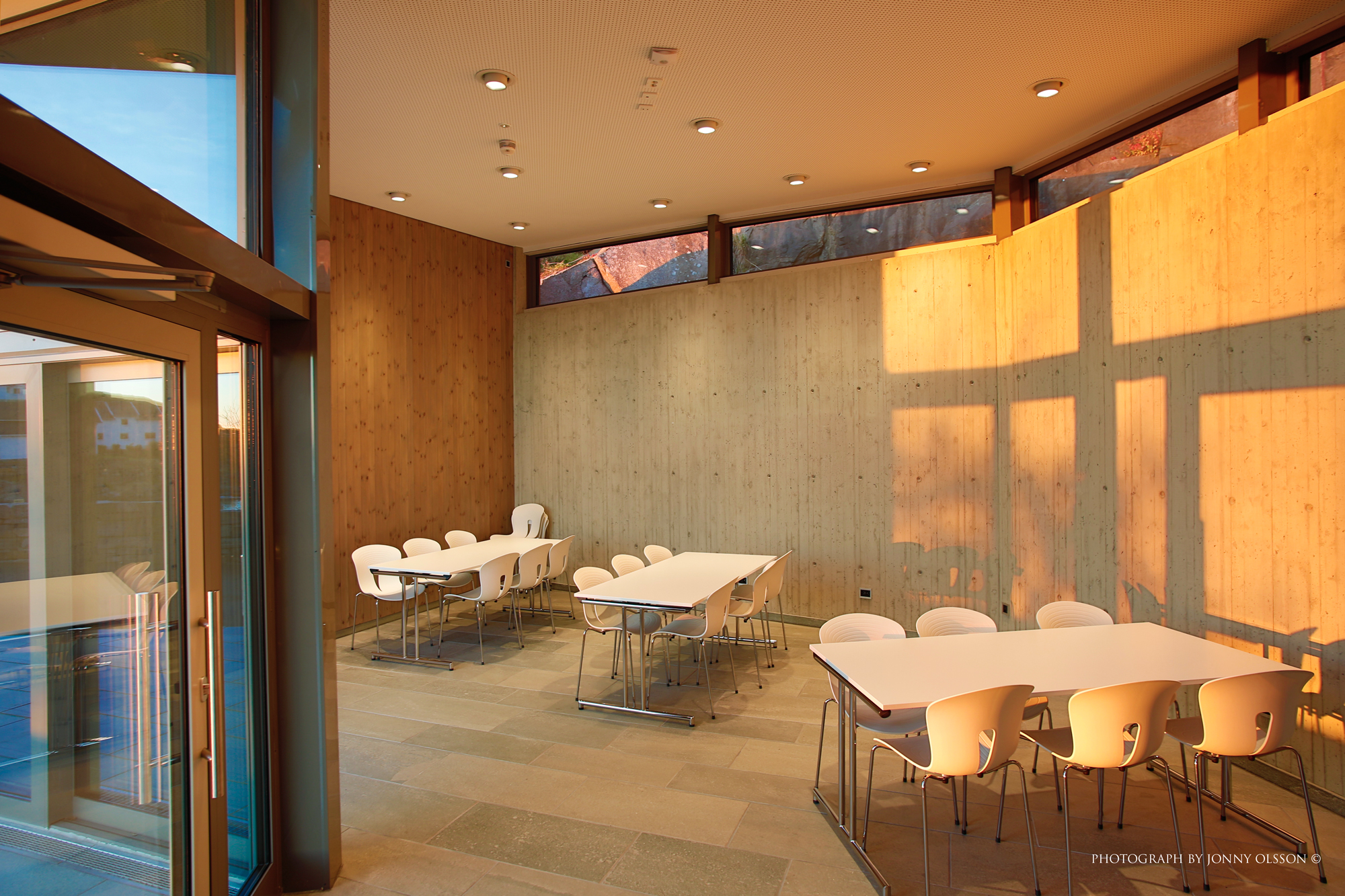 En eksponert betongvegg med høytsittetnde vinduer forklarer hvordan bygningen ligger i terrenget